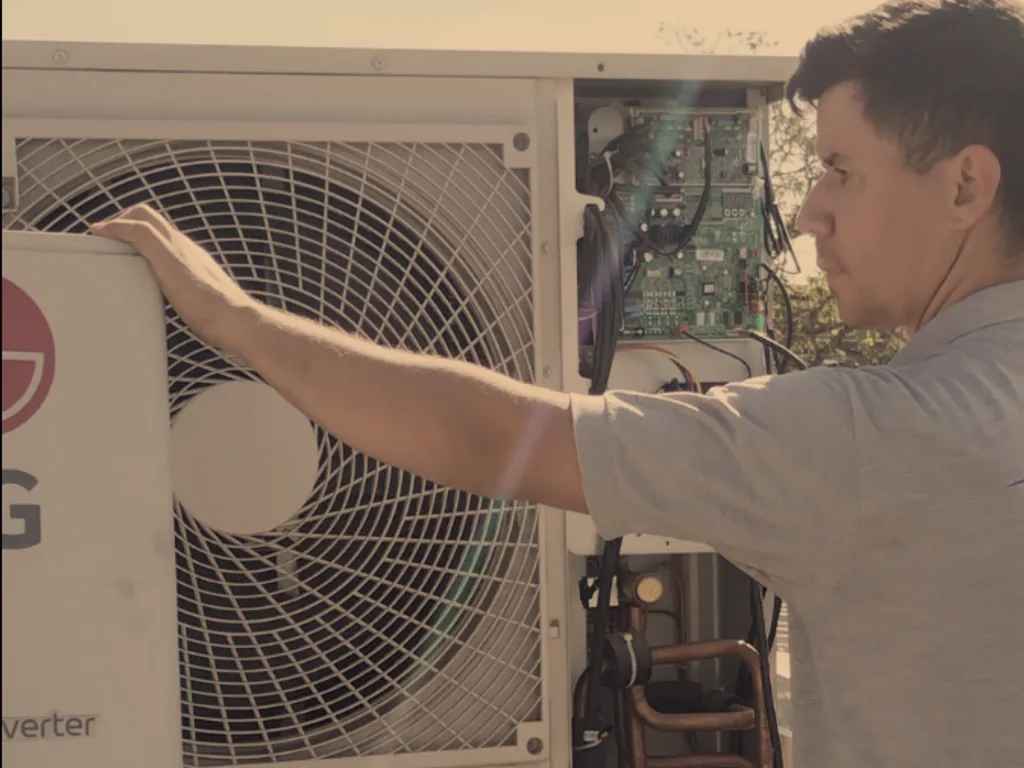 Técnico inspecionando a placa eletrônica de uma condensadora LG Dual Inverter aberta